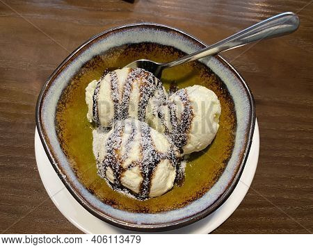 Three Melting Chocolate Ice Cream Balls In Brown Ceramic Bowl On Table In Cafe. Top View