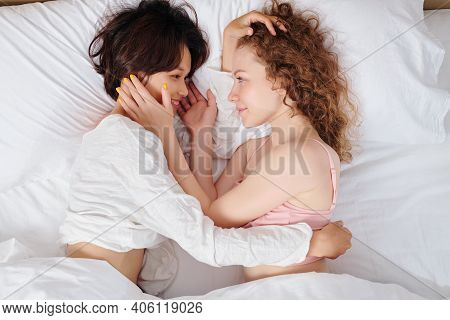 Beautiful Smiling Lesbian Girlfriends Lying In Bed And Looking At Each Other, View From Above