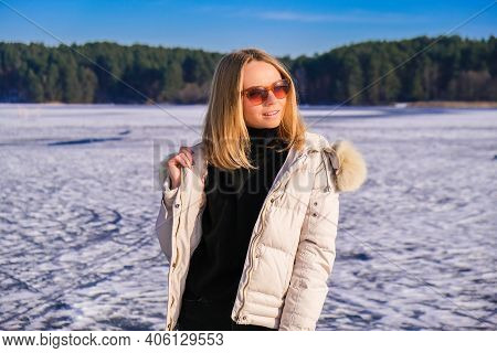 Young Female Smiling And Looking Away In Sunglasses A Snow Landscape. Happy Hipster Girl With Hip Ho