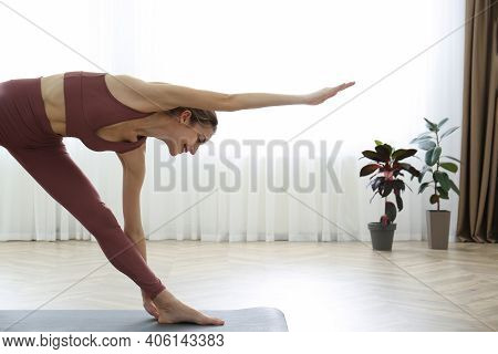 Young Woman Practicing Triangle Asana In Yoga Studio. Trikonasana Pose