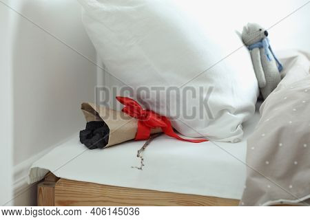 Wrapped Lumps Of Coal And Tree Twig Under Pillow In Children's Bed. St. Nicholas Day