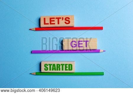 On A Blue Background, Three Colored Pencils, Three Wooden Blocks With Text Lets Get Started