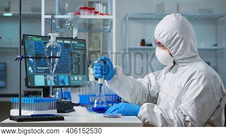 Chemist Wearing Ppe Suit Putting Liquid In Test Tube With Micropipette In Laboratory. Team Of Doctor