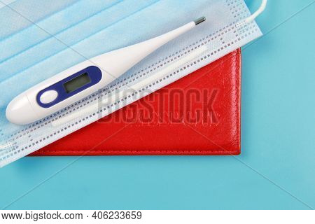 Passport, Thermometer, Disposable Medical Mask On A Blue Background. Global Problems And The Closure