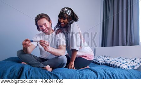 Happy Young Multiracial Couple Expecting A Baby. Positive Pregnancy Test. High Quality Photo