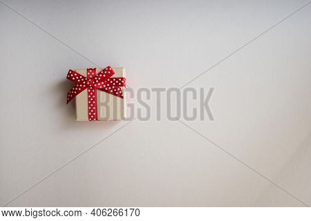 A Small Gift Box With Tied Decorative Bow And Red Ribbon On White Background.holidays Present Concep