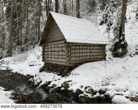 Wooden House In The Winter Forest. An Old Wooden Building. A Log House In The Middle Of A Snowy Fore