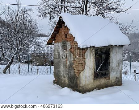 Old Brick Shed In The Snow. Rural Building In The Yard. A Covered House Is A Utility Room.