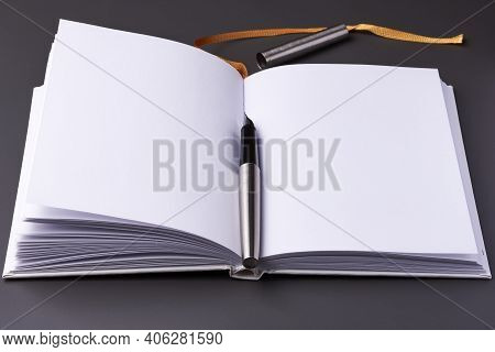 An Open Notebook With An Ink Pen On A Dark Background