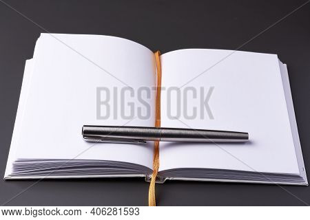 An Open Notebook With An Ink Pen On A Dark Background