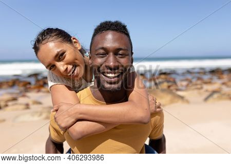 Portrait of african american couple embracing on a beach by the sea. lhealthy lifestyle, leisure in nature.