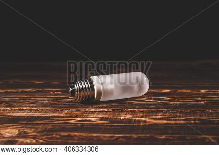 White Frosted Flash Pilot Lamp On A Wooden Background. Studio Photo In Hard Light.