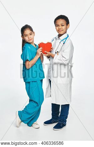 Group Of Multiethnic Kids Wearing Medical Uniforms, Kids Hold Shape Of Heart In Hands. Future Cardia