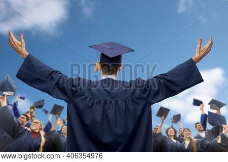 education, graduation and people concept - male graduate student over group of happy international students in bachelor gowns waving mortar boards or hats over blue sky and clouds background
