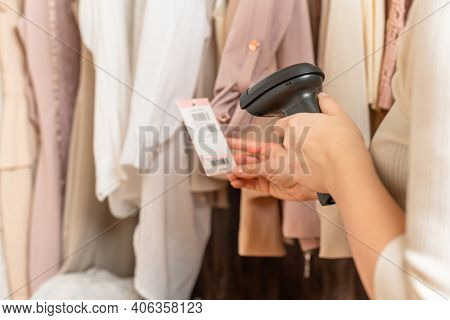 A Warehouse Woman Employee Accepts Clothes Using Barcode Scanner Reading A Bar Code From Price Tag O