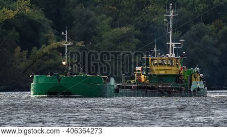 Scow On The Waterway - A Barge Flowing Along The Canal Against The Background Of The Forest