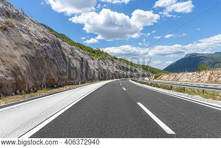 Highway With Blue Sky And Rocky Mountains On A Background