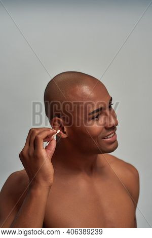 Concerned Man Of Sportive Complection Sticking A Cotton Bud In Right Ear While Turning His Head