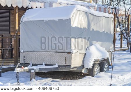 Motorhome Rv, Trailer, Campervan Parked Near House Under Snow In Winter.