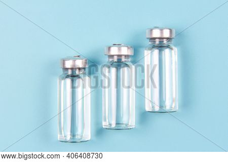 Vials Of Medicines On A Blue Background. The Covid-19 Coronavirus Vaccine. The Concept Of Prevention