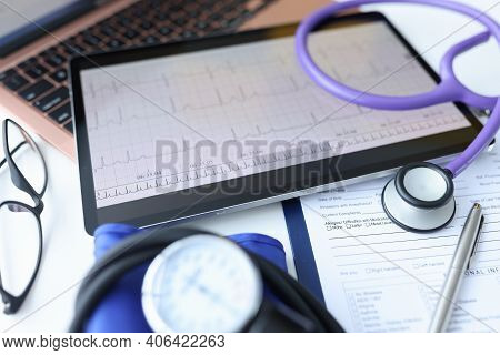Digital Tablet With Electrocardiogram Lying On Doctors Desk Closeup. Ecg Diagnosis Of Rhythm Disturb