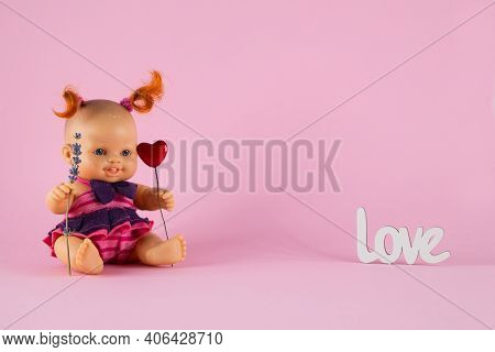 Freckled White Doll Girl With Two Curly Red Tails Holds A Heart And A Sprig Of Lavender On A Pink Ba