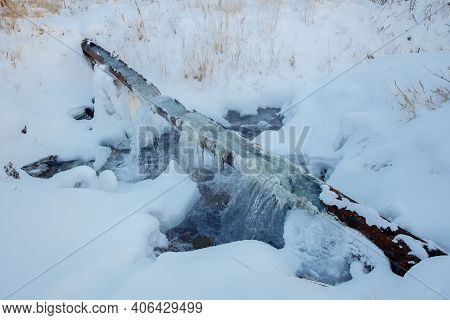 Break Of A Communal Water Pipe In The Winter. Pure Water Flows From A Rusty Pipe. There Is Snow All 