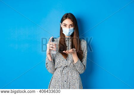 Covid-19, Social Distancing And Healthcare Concept. Beautiful Girl In Medical Mask Using Hand Sanizi