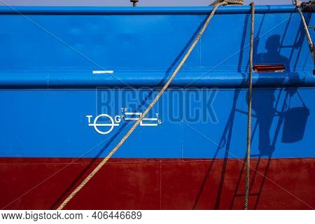 Sunlight And Shadow Of Painter Climbing Ladder With White Plimsoll Mark On Blue And Red Rust Proof S