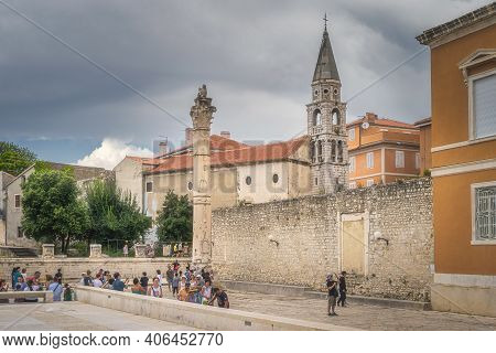 Zadar, Croatia, July 2019 Tourists Admiring And Photographing Old Roman Ruins, A Column With Sculptu