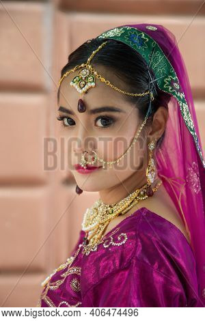 Portrait Asian Woman In A Margenta Indian Tradition Sari, She Is Looking At A Camera Next To The Whi