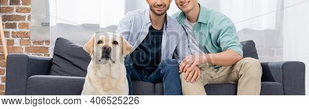 Cropped View Of Same Sex Couple Sitting On Sofa Near Dog, Banner.