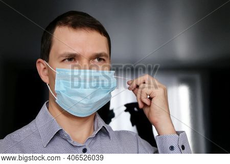Man In Office Clothes Removing Medical Face Mask. Concept Of Violation Of Safety Measures During Cor
