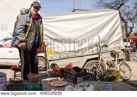 Sombor, Serbia - March 19, 2016: Senior Old Man Selling Farm Products, Food, On A Stall, Holding A L