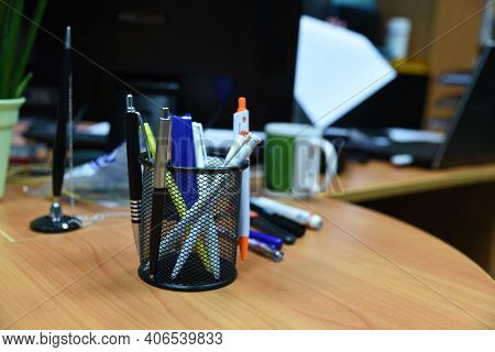 Pencils And Pens In Plastic Glass On The Wooden Table In The Office. Plastic Box For Storing Artific