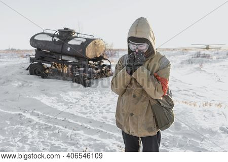 Errant Young Man In Winter Post-apocalyptic World. A Homeless Boy. Boy In A Protective Jacket With A