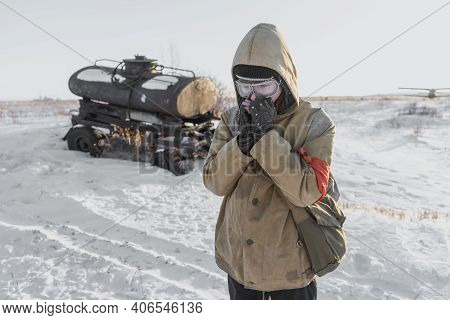 Errant Young Man In Winter Post-apocalyptic World. A Homeless Boy. Boy In A Protective Jacket With A