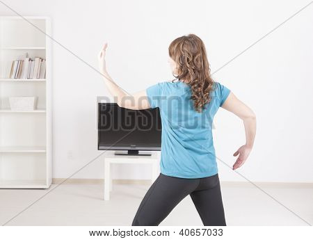 Kvinden laver yoga exerise derhjemme ved hjælp af instruktionerne på skærmen TV