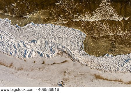Aerial view over partialy frozen sea with white ice texture