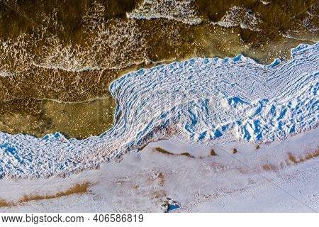 Aerial view over partialy frozen sea with white ice texture