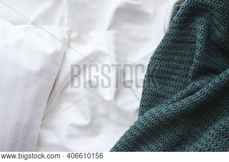 Top View Of An Unmade Bed With Rumpled Sheet, Knitted Blanket, And Pillow. Good Morning Or Good Nigh