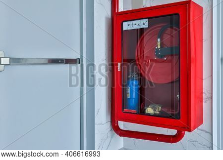 Hydrant With Water Hoses And Fire Extinguish Equipment. Fire Safety Equipment In The Red Box On Wall