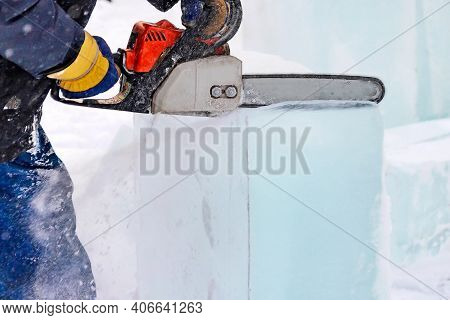 A Worker With A Chainsaw In Hand Cuts The Ice Block.