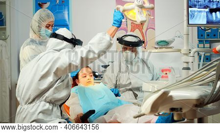 Dentist Technician In Coverall Drilling Kid Tooth In Dental Clinic During Coronavirus Pandemic. Conc