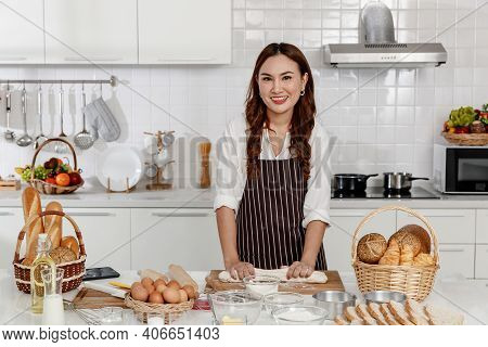 Asian Middle-aged Woman Kneading Dough For Baking Happy And Smile In The Home Kitchen. Concept Desse