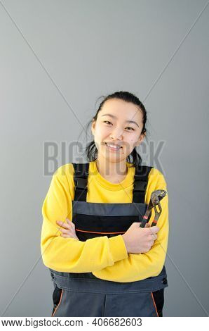 Female Construction Worker Dressed In Special Clothes With A Cordless Screwgun, A Construction Tool 