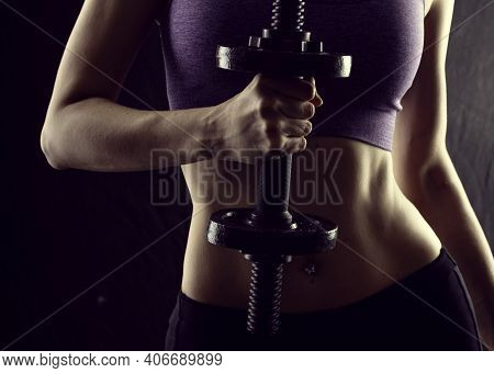 Slim Athletic Woman Holding Dumbbell In The Hand On Black