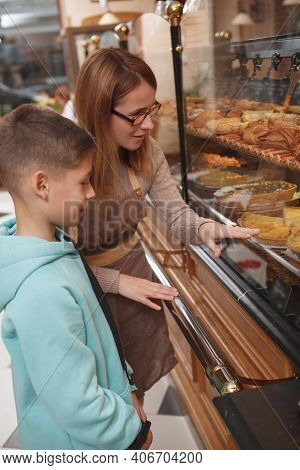 Vertical Shot Of A Professiona Baker Showing Delicious Pastry To Her Young Customer