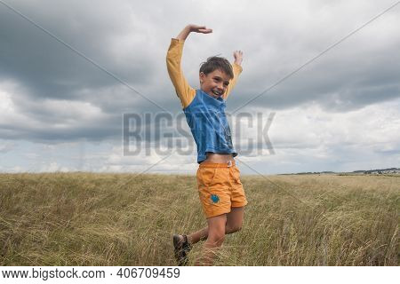 Boy In Shorts Stands In The Field. Boy Looks To The Sky. Dreamer Guy