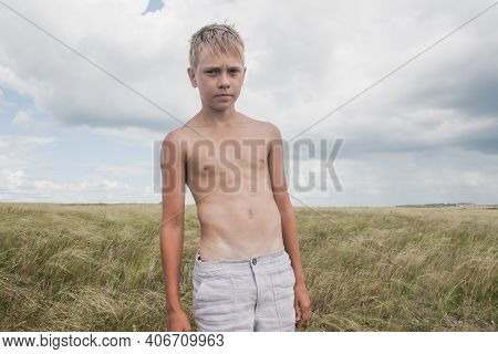 Boy In Shorts Stands In The Field. Boy Looks To The Sky. Dreamer Guy
